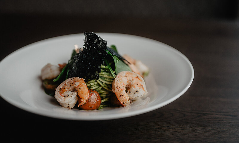 Saftige Garnelen auf Pasta mit frischen Tomaten und knusprigen Akzenten im Hotel Berghof.