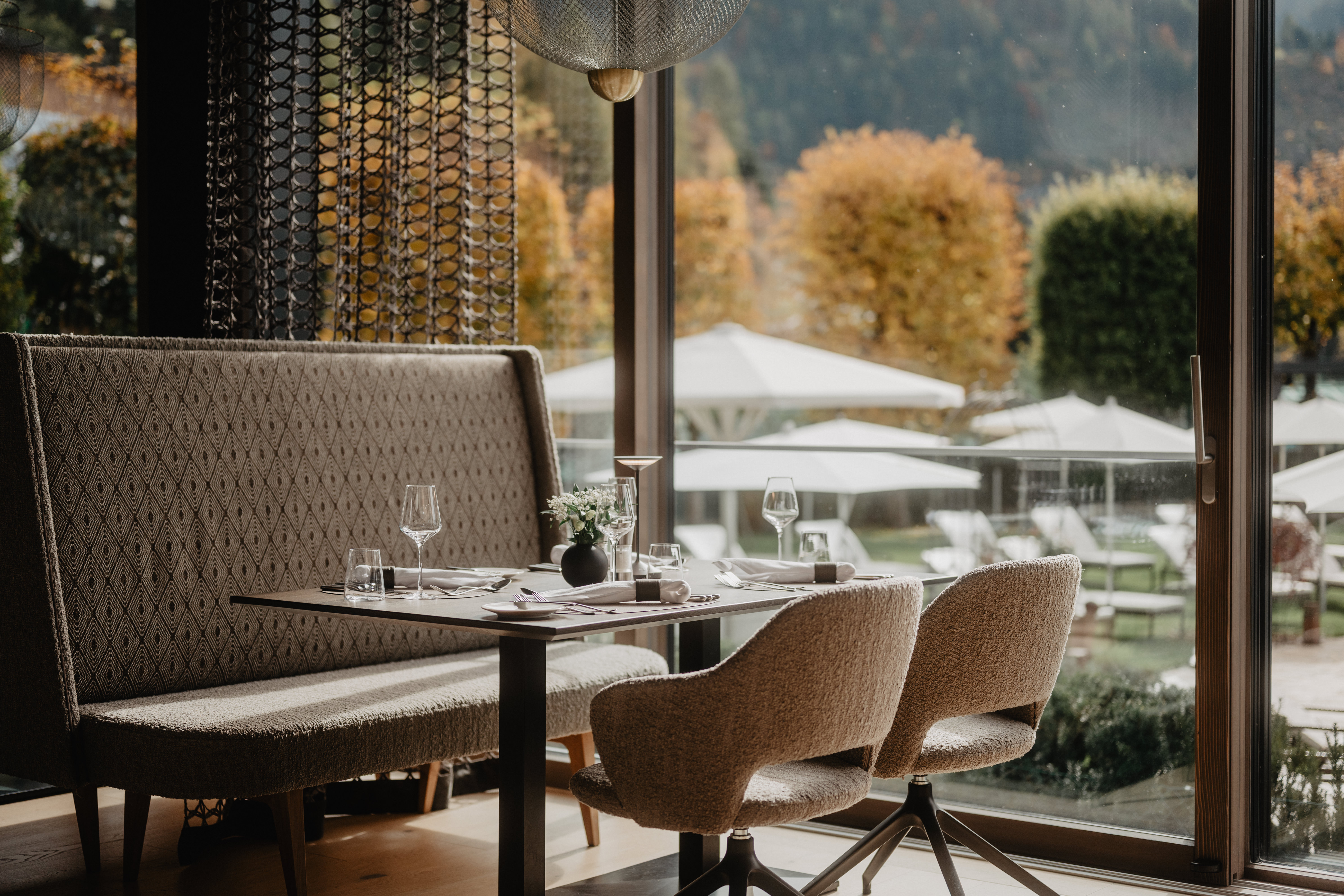 Ein Restaurant mit aufgedecktem Tisch und Blick auf herbstliche Kulisse.